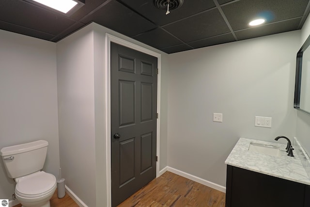 bathroom featuring vanity, hardwood / wood-style floors, toilet, and a paneled ceiling