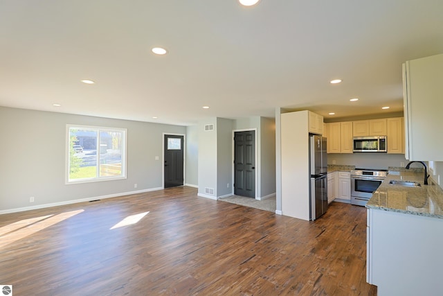 kitchen with light stone countertops, stainless steel appliances, white cabinets, dark wood-type flooring, and sink