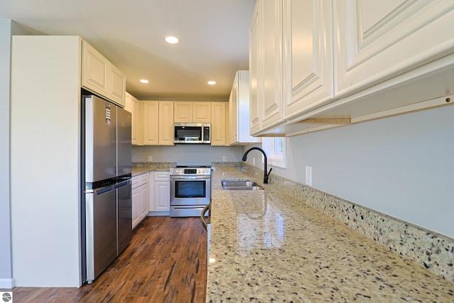 kitchen with dark hardwood / wood-style flooring, sink, stainless steel appliances, light stone countertops, and white cabinets