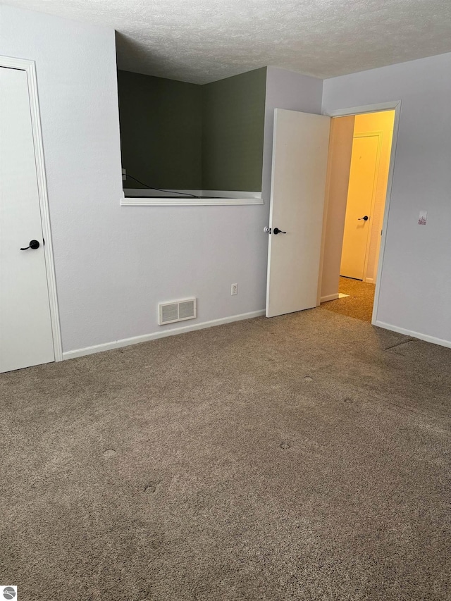 carpeted spare room featuring a textured ceiling