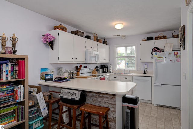 kitchen featuring sink, white appliances, kitchen peninsula, and white cabinets