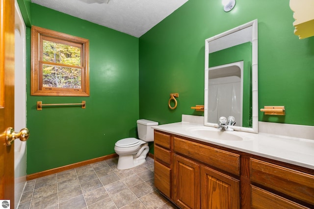 bathroom featuring toilet, a textured ceiling, and vanity