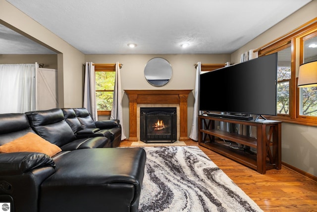 living room featuring light hardwood / wood-style floors, a textured ceiling, and a tile fireplace