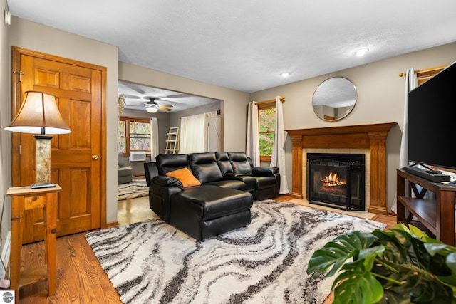 living room with a wealth of natural light, light hardwood / wood-style flooring, a fireplace, and ceiling fan