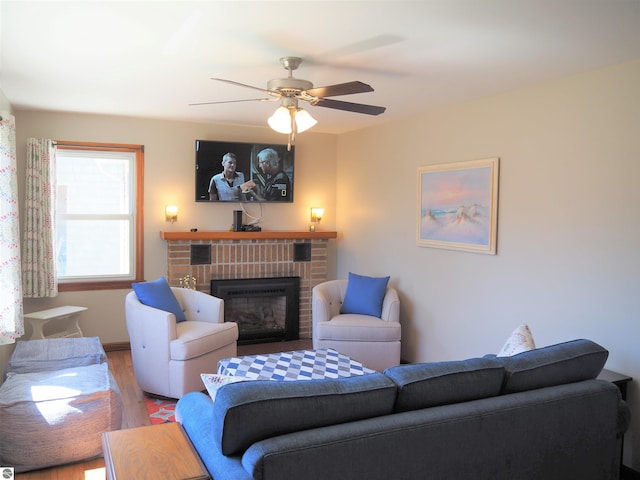 living room with ceiling fan, hardwood / wood-style flooring, and a brick fireplace