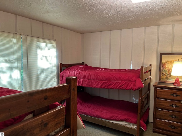 bedroom with carpet flooring, wood walls, and a textured ceiling