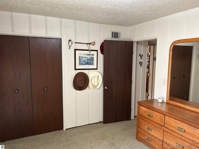 unfurnished bedroom featuring a textured ceiling, light colored carpet, and a closet