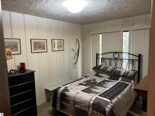 carpeted bedroom featuring wood walls and a textured ceiling