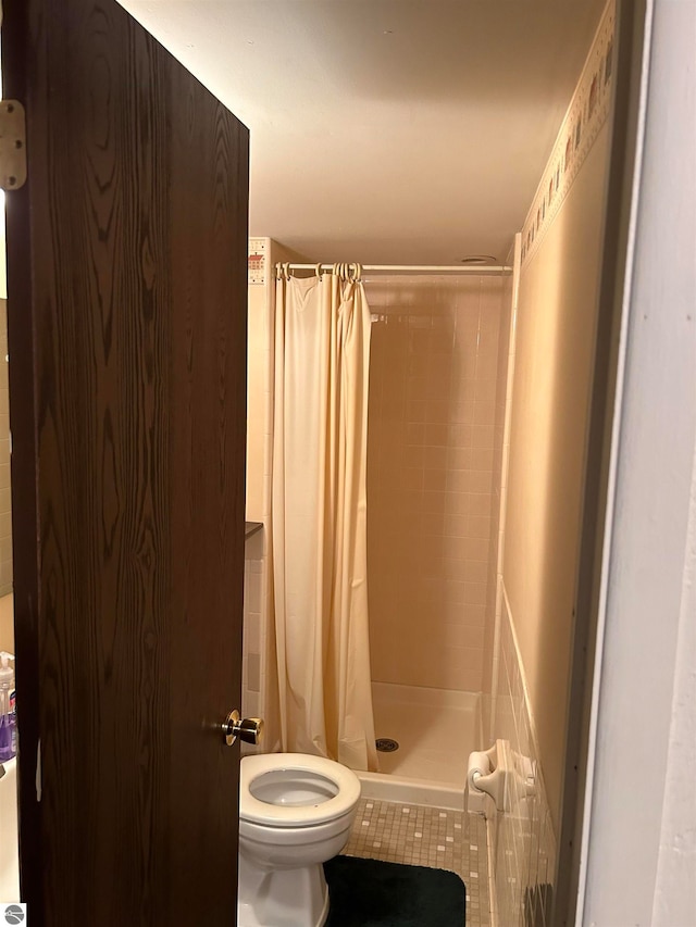 bathroom featuring a shower with shower curtain, tile patterned flooring, and toilet