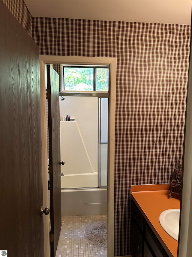 bathroom with tile patterned floors, shower / bath combination with glass door, and vanity