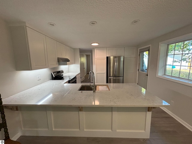 kitchen with dark wood-type flooring, light stone counters, appliances with stainless steel finishes, and white cabinets