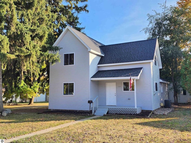 traditional-style home with central AC unit, a front yard, and a shingled roof