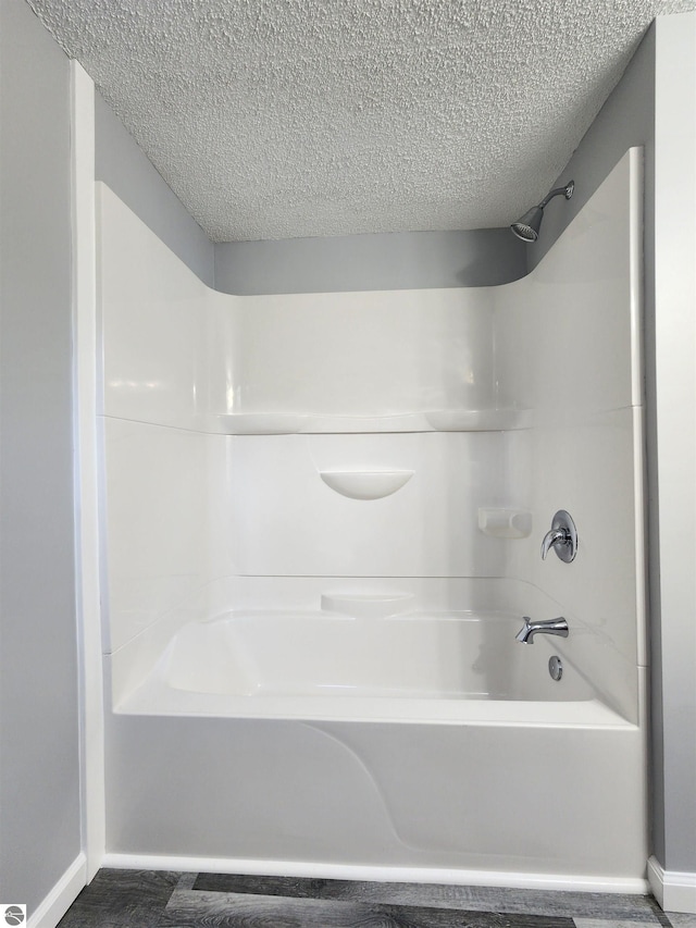 bathroom with washtub / shower combination and a textured ceiling