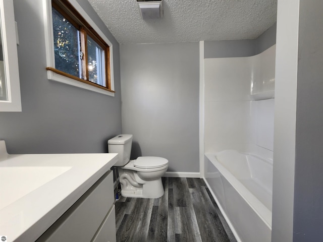 full bathroom with hardwood / wood-style floors, a textured ceiling, toilet, shower / bathtub combination, and vanity