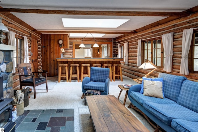 living room featuring beam ceiling, plenty of natural light, rustic walls, and bar area