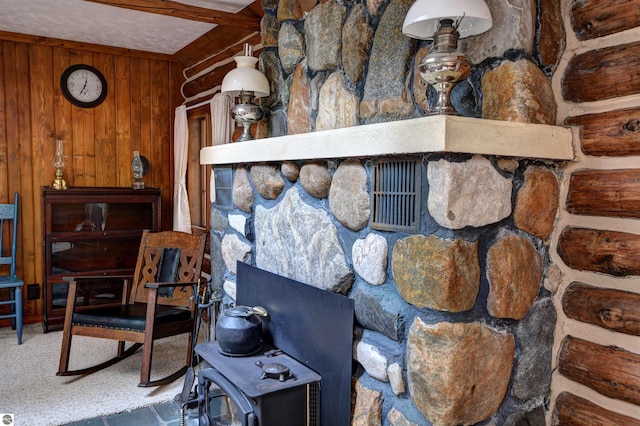 room details with beam ceiling, wood walls, and a wood stove