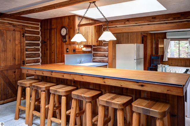 kitchen featuring a wall mounted air conditioner, butcher block counters, white fridge, and a breakfast bar area