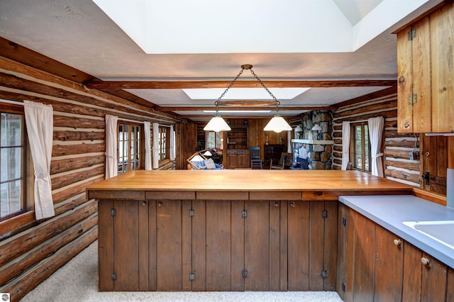 kitchen with butcher block counters, carpet flooring, rustic walls, and hanging light fixtures