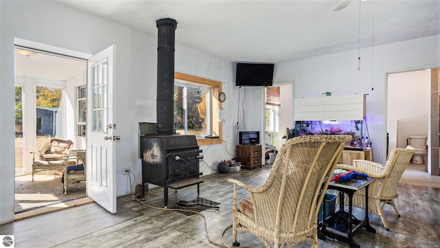 living room with hardwood / wood-style floors, ceiling fan, a wood stove, and plenty of natural light