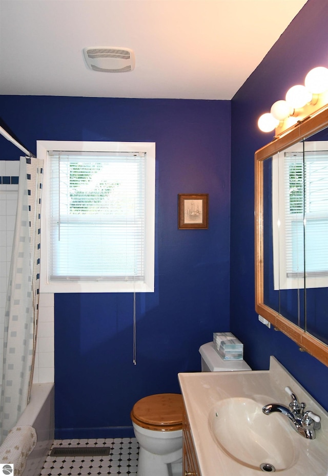 full bathroom featuring toilet, a healthy amount of sunlight, vanity, and shower / tub combo