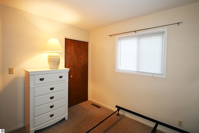 unfurnished bedroom featuring a closet and dark carpet