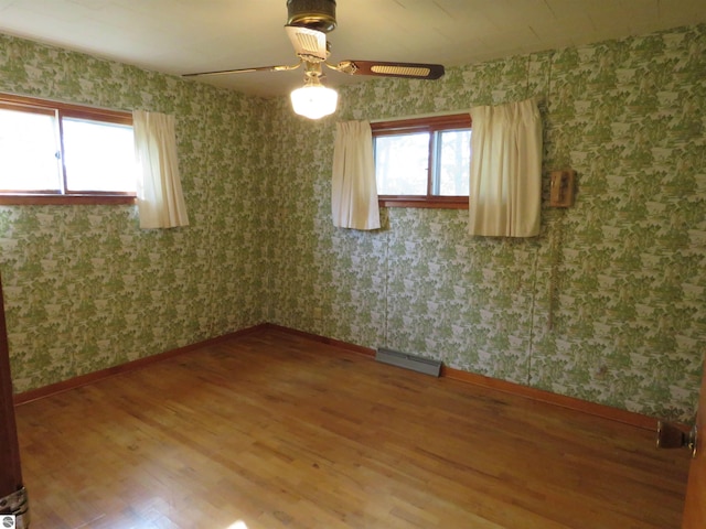 unfurnished room with a wealth of natural light, hardwood / wood-style floors, and ceiling fan