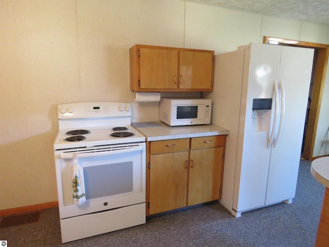 kitchen featuring dark colored carpet and white appliances