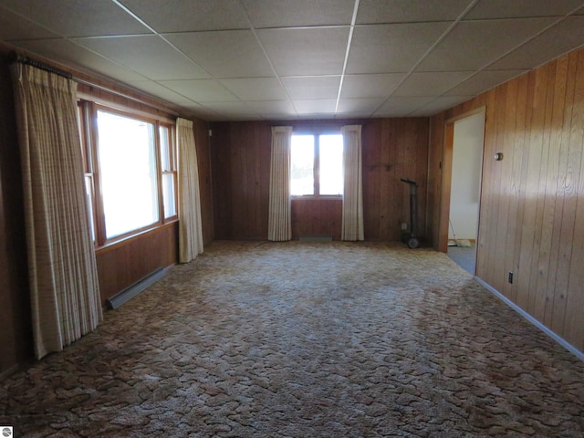 unfurnished room with wood walls and a paneled ceiling