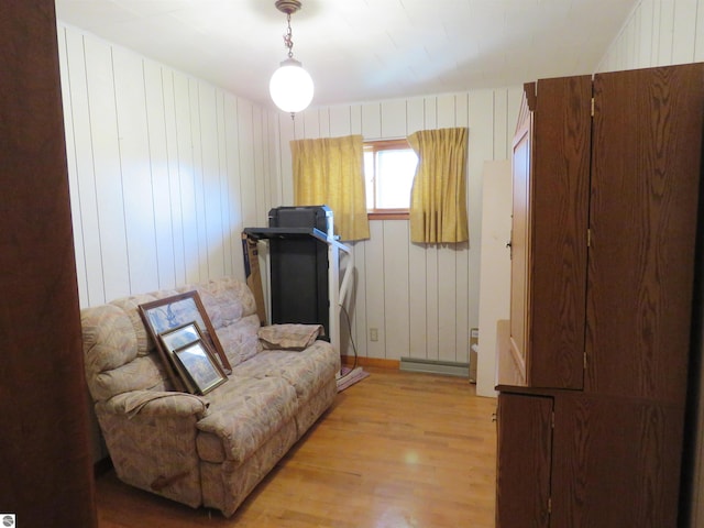 sitting room with light hardwood / wood-style flooring, wooden walls, and a baseboard radiator