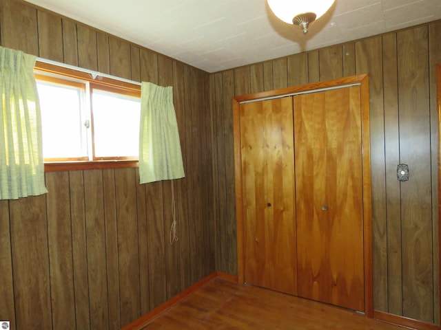 unfurnished bedroom with wood walls and hardwood / wood-style floors