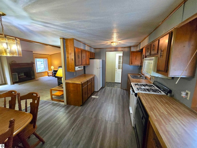 kitchen with a textured ceiling, dark hardwood / wood-style floors, decorative light fixtures, sink, and white appliances