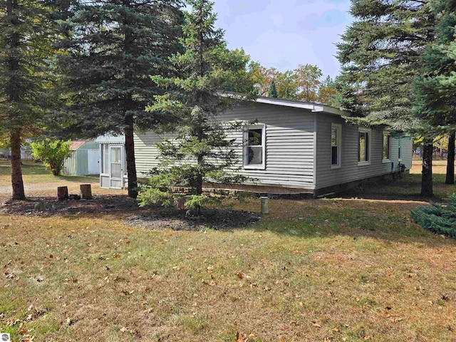 view of side of property with a yard and a shed