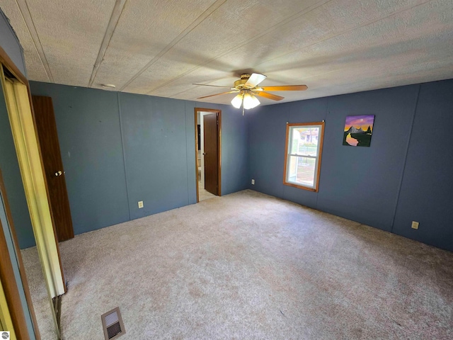 carpeted empty room with a textured ceiling and ceiling fan