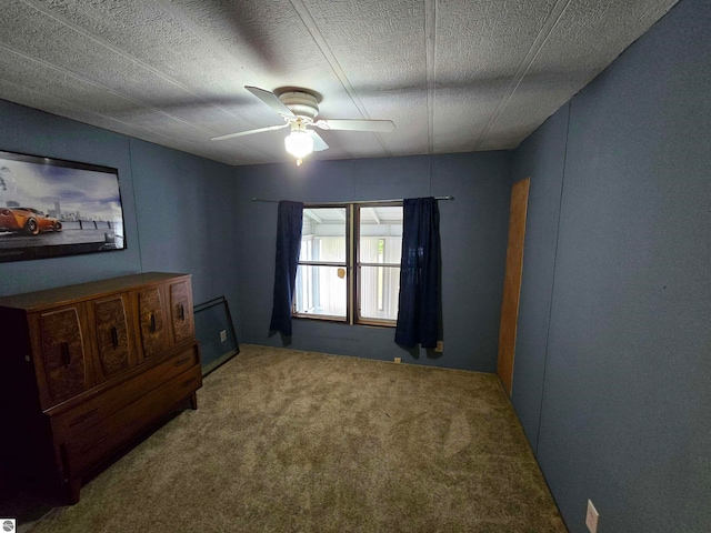 interior space with a textured ceiling, carpet flooring, and ceiling fan