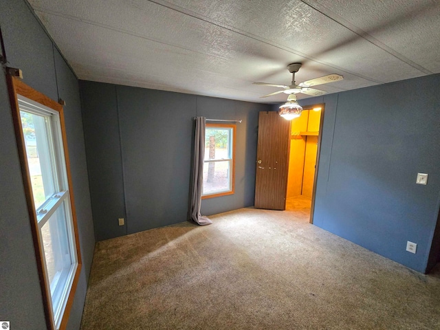 empty room featuring ceiling fan, carpet floors, and plenty of natural light