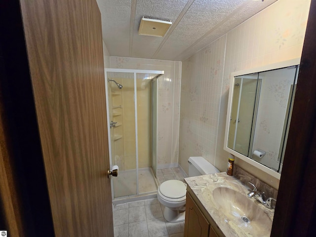 bathroom featuring vanity, toilet, a textured ceiling, and a shower with door