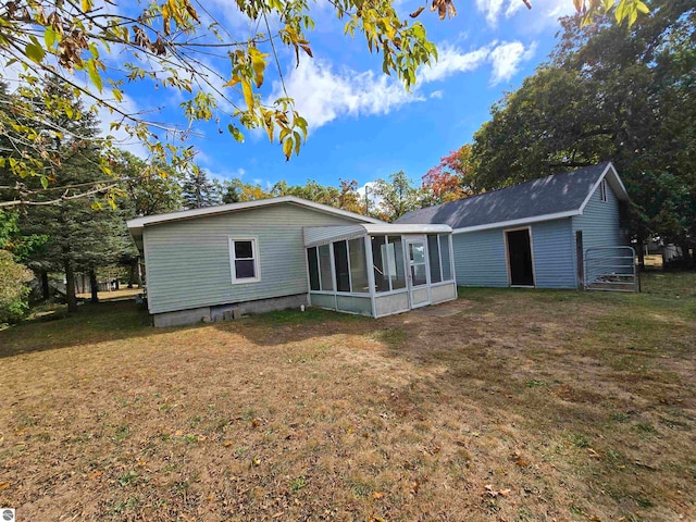 rear view of house featuring a sunroom and a lawn