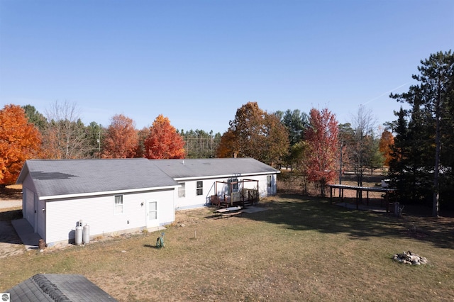 back of house with a lawn and a trampoline