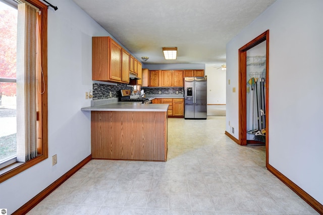 kitchen with tasteful backsplash, kitchen peninsula, ceiling fan, and appliances with stainless steel finishes