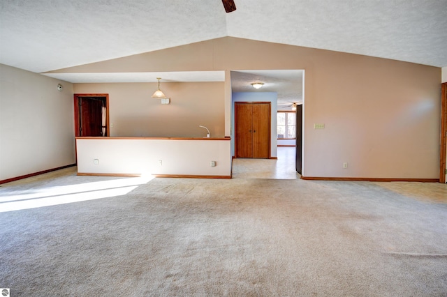 carpeted empty room featuring a textured ceiling, ceiling fan, and vaulted ceiling