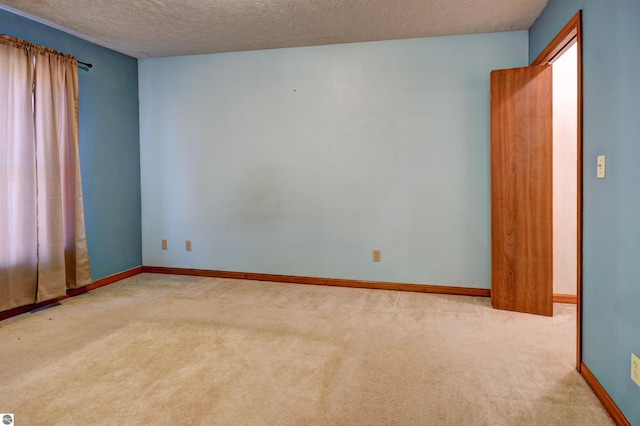 unfurnished room with light carpet and a textured ceiling