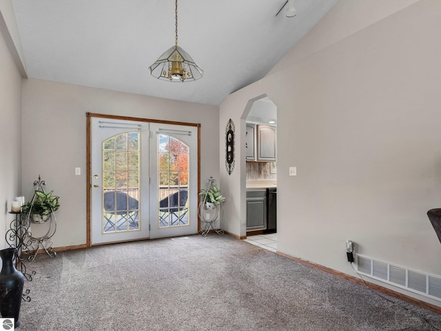 doorway featuring light carpet, vaulted ceiling, and an inviting chandelier