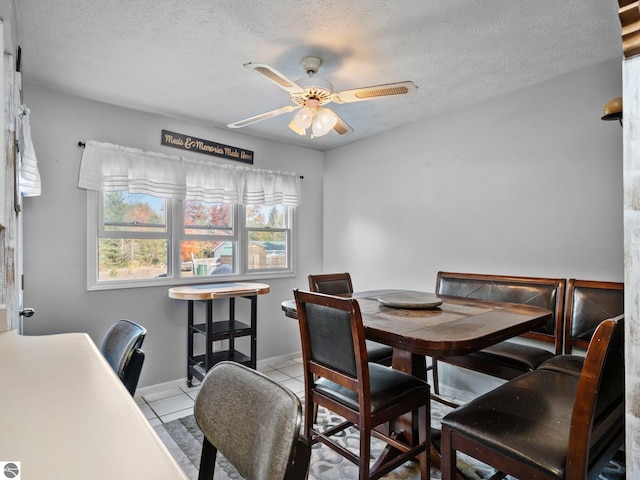 dining space with ceiling fan, a textured ceiling, and light tile patterned floors