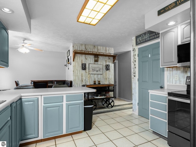 kitchen with blue cabinetry, electric range, light tile patterned flooring, and ceiling fan