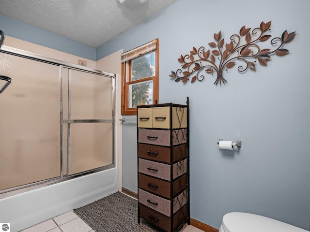 bathroom featuring bath / shower combo with glass door, a textured ceiling, toilet, and tile patterned flooring