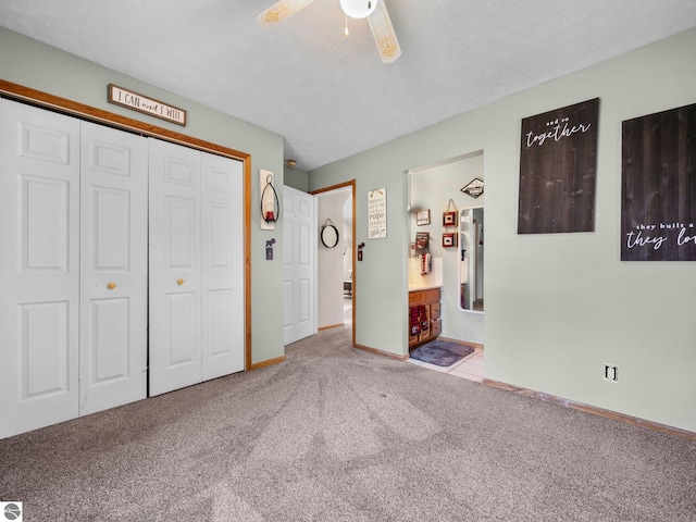 unfurnished bedroom featuring a closet, carpet flooring, ensuite bathroom, a textured ceiling, and ceiling fan