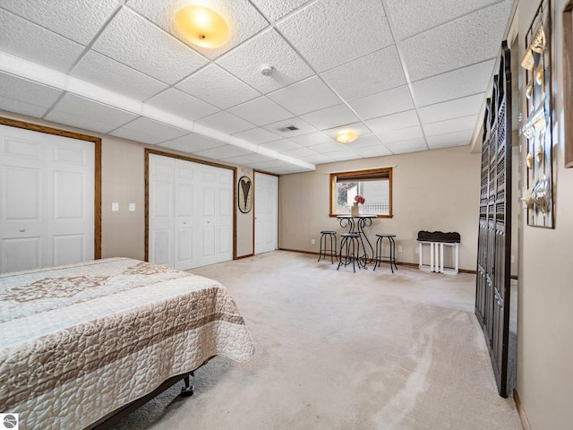 carpeted bedroom with a drop ceiling and a closet