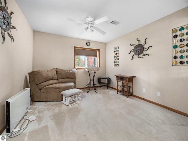 living area featuring light carpet, heating unit, and ceiling fan