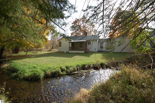 rear view of house with covered porch and a lawn