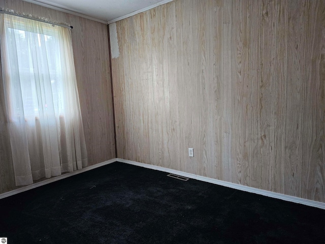 carpeted spare room with wooden walls